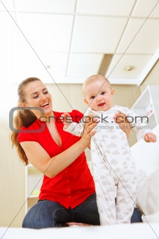 Smiling mother helping baby learn to walk
