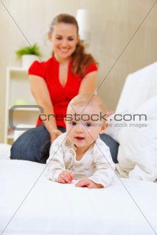 Smiling mother and adorable baby playing on sofa
