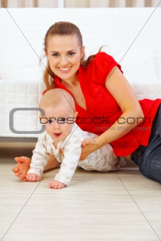 Happy mother and lovely baby playing on floor
