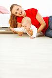 Young mother and cheerful baby playing on floor
