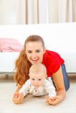 Smiling mommy and adorable baby playing on floor
