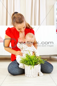 Smiling mommy showing plant to her baby
