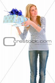 Interested teen girl shaking present box trying to guess what's inside
