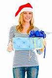 Pretty teen girl in Santa hat presenting gift
