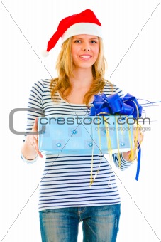 Pretty teen girl in Santa hat presenting gift
