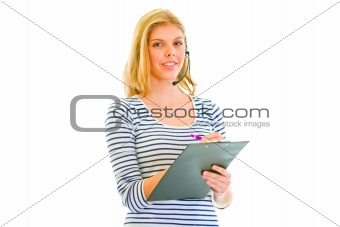 Pretty teen girl in headset writing in clipboard
