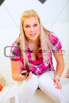 Excited young woman sitting on couch and watching TV
