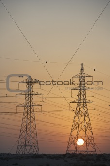 Electricity Pylons Silhouetted At Sunset