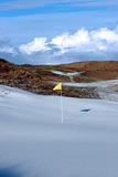 cold snow covered links golf course with yellow flag