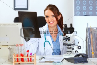 Smiling female medical doctor sitting at office table with patients roentgen
