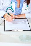 Close up on medical doctor woman sitting at office table and working with document
