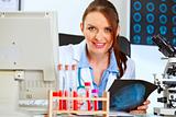 Happy doctor woman sitting at office table with patients roentgen
