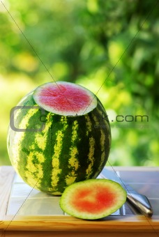 Watermelon and knife on table.