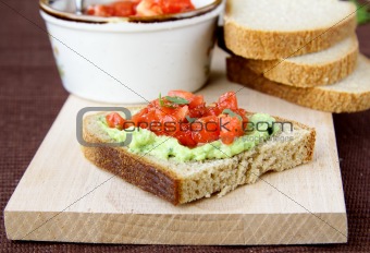 sandwich with avocado and tomato on a wooden board