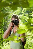 young female photographer hiking in forest 