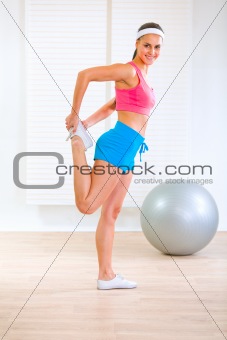 Smiling fitness girl doing stretching exercises at home
