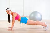 Happy fitness girl making push-up exercises at home