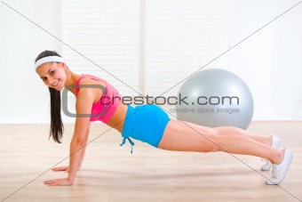 Happy fitness girl making push-up exercises at home
