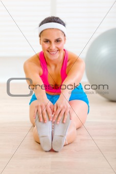 Happy young female doing exercises on floor at home
