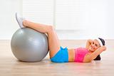 Smiling fit girl doing abdominal crunch on fitness ball
