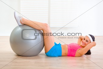 Smiling fit girl doing abdominal crunch on fitness ball
