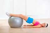 Smiling young woman doing abdominal crunch on fitness ball
