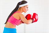 Concentrated fitness woman in boxing gloves working out

