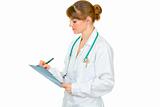 Medical female doctor writing in medical chart
