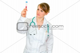 Pensive medical female doctor looking on test tube
