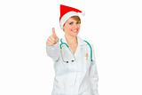 Smiling medical female doctor in Santa hat showing thumbs up
