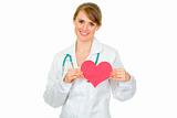 Smiling medical doctor woman holding paper heart
