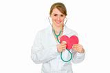 Happy medical female doctor holding stethoscope on paper heart
