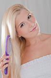 Beautiful woman with healthy blond hair brushing