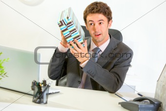 Interested businessman shaking present box trying to guess what's inside
