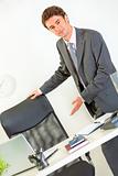 Modern businessman offering to seat at office desk

