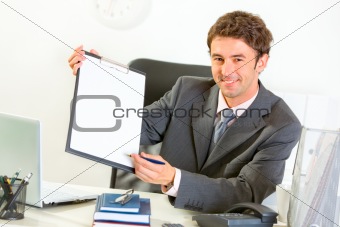 Smiling businessman giving clipboard and pen for signing

