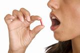 young women pops a pill into her mouth