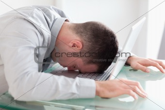 Close up of overworked businessman taking a nap on his laptop