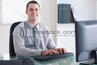 Smiling businessman typing on his computer