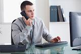Businessman listening to caller while typing