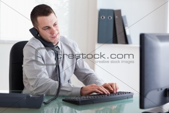 Businessman on the telephone and typing on his computer