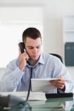 Close up of businessman looking at a letter while on the phone