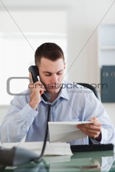 Close up of businessman looking at a letter while on the phone
