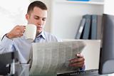 Businessman having a coffee while reading the newspaper