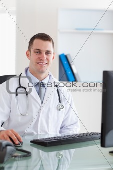 Smiling doctor sitting on his computer