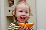 little girl laughing and eating grapefruit