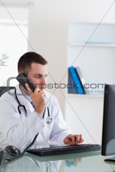 Doctor on the telephone while looking at the screen