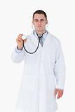 Serious looking doctor using stethoscope