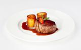 beef filet with fondant potato and red wine sauce on a white plate