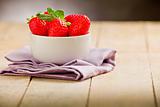 Strawberries on wooden table with violet napkin